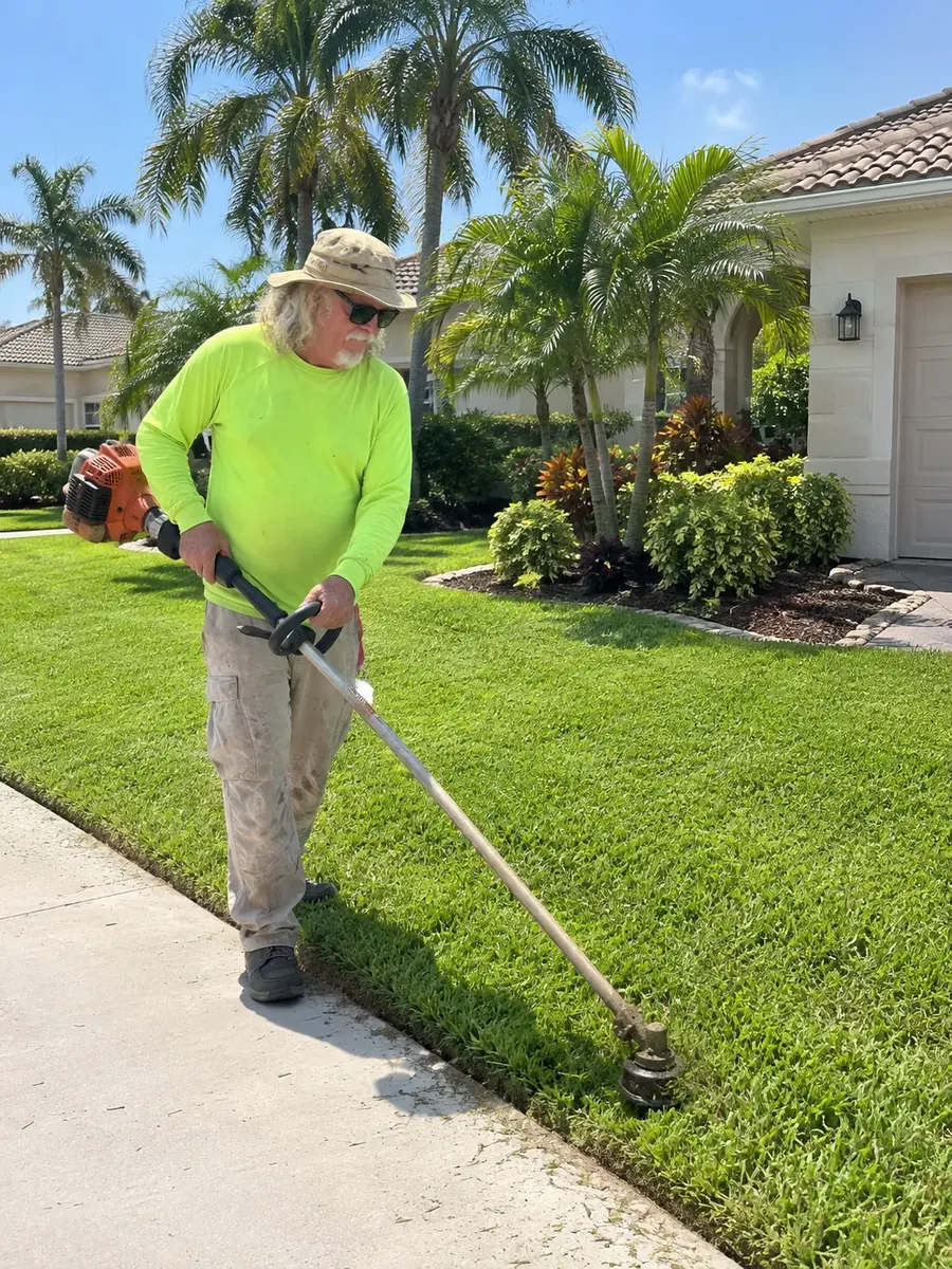 Tim edging a lawn along the sidewalk with a string trimmer